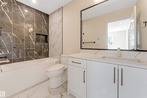 Contemporary bathroom featuring a white porcelain tub, dark marbled shower surround, and a coordinating vanity with a white countertop and gold-toned hardware - 10323 79 Street, Edmonton, AB - Indoor Photo Showing Bathroom