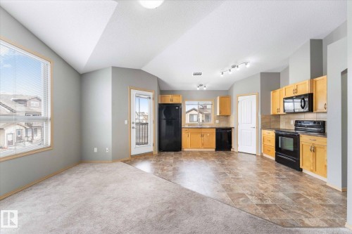 Kitchen featuring wood cabinetry, black appliances, tile flooring, and a tile backsplash - 86 604 62 Street, Edmonton, AB - Indoor Photo Showing Kitchen