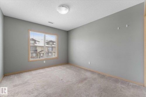 Neutral gray walls with light brown carpeting, featuring a ceiling-mounted light fixture, white trim, and a ceiling vent - 86 604 62 Street, Edmonton, AB - Indoor Photo Showing Other Room
