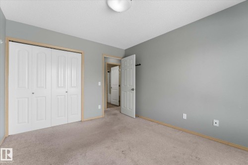 Carpeted room featuring light gray walls, a textured ceiling, and a white interior door with paneling - 86 604 62 Street, Edmonton, AB - Indoor Photo Showing Other Room
