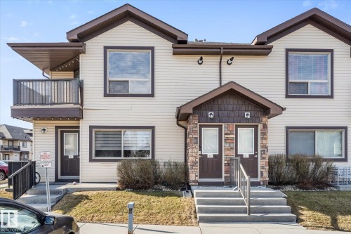 Two-story multi-unit structure featuring light-colored siding with dark trim, dual front entrances with covered porticos, and individual balconies - 86 604 62 Street, Edmonton, AB - Outdoor With Facade