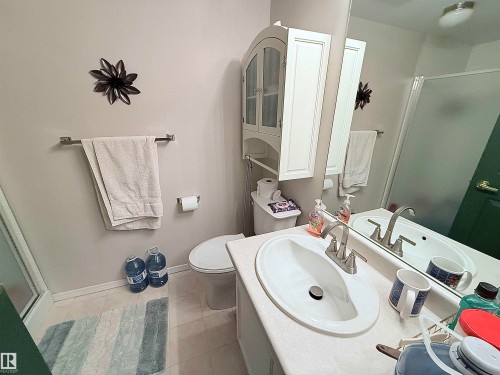 Bathroom featuring a white vanity with an oval sink, brushed nickel faucet, and a large wall-mounted mirror - 410 9926 100 Avenue, Fort Saskatchewan, AB - Indoor Photo Showing Bathroom