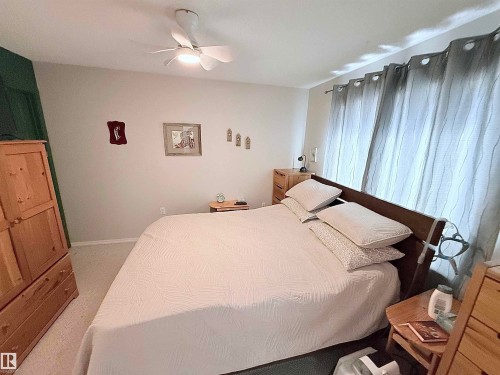 Spacious bedroom featuring light-colored walls, a ceiling fan with integrated lighting, and soft carpet flooring - 410 9926 100 Avenue, Fort Saskatchewan, AB - Indoor Photo Showing Bedroom