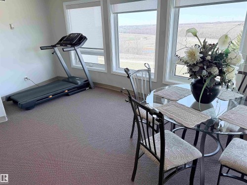 Room featuring multiple windows, neutral tone carpeting, and light gray wall paint - 410 9926 100 Avenue, Fort Saskatchewan, AB - Indoor Photo Showing Gym Room