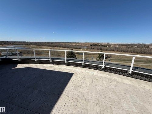 Expansive outdoor patio featuring a light-toned, interlocking tile surface and a glass railing system - 410 9926 100 Avenue, Fort Saskatchewan, AB - Outdoor With View