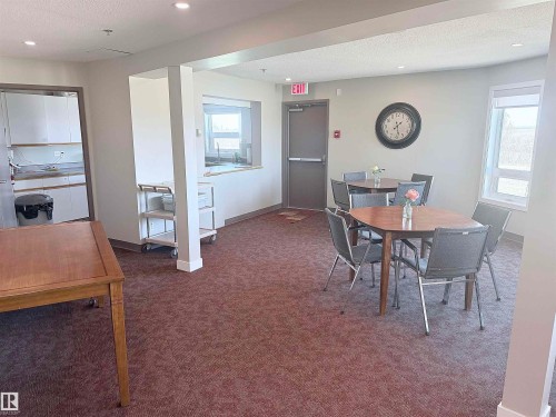 Spacious common area featuring textured carpeting, recessed lighting, and ample natural light from multiple windows - 410 9926 100 Avenue, Fort Saskatchewan, AB - Indoor