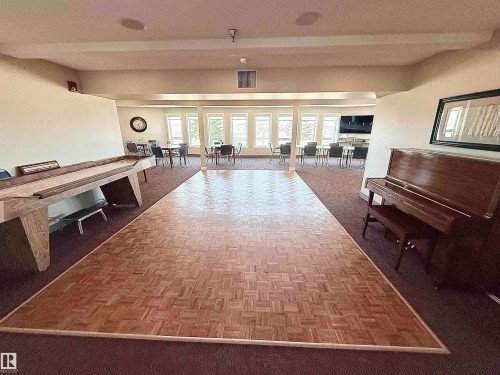 Spacious common area featuring a parquet wood-finish dance floor, expansive window-line, integrated ceiling speakers, and recessed lighting - 410 9926 100 Avenue, Fort Saskatchewan, AB - Indoor Photo Showing Other Room