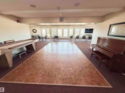 Spacious common area featuring a parquet wood-finish dance floor, expansive window-line, integrated ceiling speakers, and recessed lighting - 