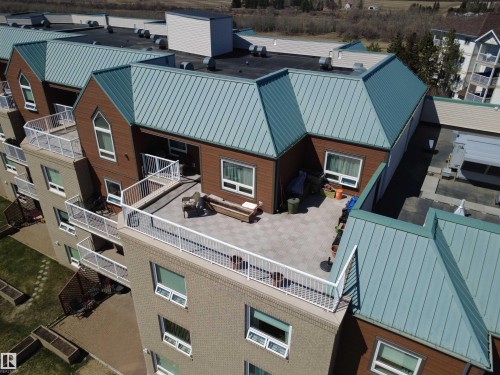 Expansive outdoor patio featuring gray pavers, white railings, and direct access to the interior - 410 9926 100 Avenue, Fort Saskatchewan, AB - Outdoor