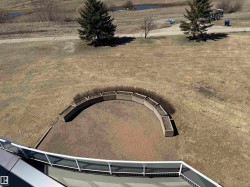 Paved patio with curved stone planters and expansive outdoor space - 