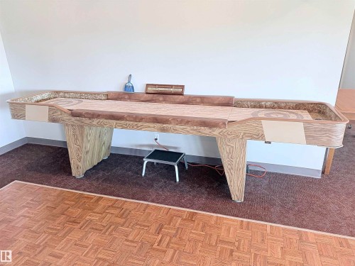 Spacious room featuring a shuffleboard table with a light wood-finish base and a textured playing surface - 410 9926 100 Avenue, Fort Saskatchewan, AB - Indoor Photo Showing Other Room