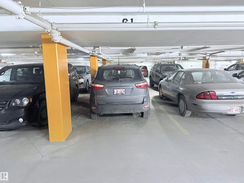 Underground parking garage featuring concrete flooring, exposed overhead piping, and structural support columns - 410 9926 100 Avenue, Fort Saskatchewan, AB - Indoor Photo Showing Garage