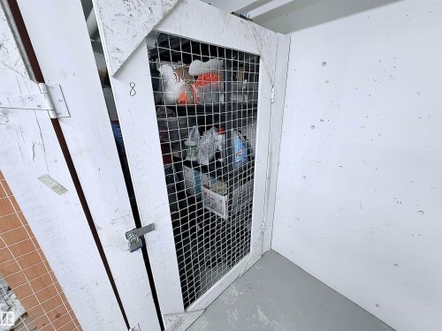 Enclosed storage unit with a white wire mesh door and painted concrete walls - 410 9926 100 Avenue, Fort Saskatchewan, AB - Outdoor