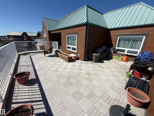 Outdoor patio featuring light-toned square pavers, partial wood-finish decking, and a white railing - 410 9926 100 Avenue, Fort Saskatchewan, AB - Outdoor With Deck Patio Veranda With Exterior