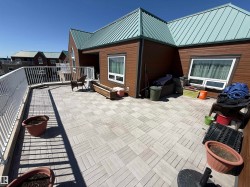 Outdoor patio featuring light-toned square pavers, partial wood-finish decking, and a white railing - 
