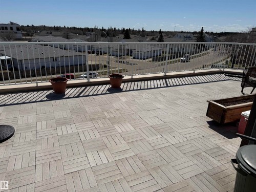 Expansive rooftop patio featuring interlocking wood-finish tiles and a white metal railing - 410 9926 100 Avenue, Fort Saskatchewan, AB - Outdoor