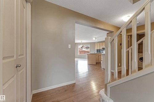 Entryway featuring wood-finish flooring, a white paneled closet door, and a staircase with white spindles and a carpeted runner - 1431 Hodgson Way, Edmonton, AB - Indoor Photo Showing Other Room