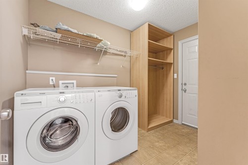 Dedicated laundry area featuring tile flooring, built-in shelving, a clothes rod, and wire shelving - 1431 Hodgson Way, Edmonton, AB - Indoor Photo Showing Laundry Room