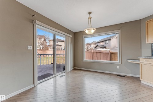 Bright interior space featuring wood-finish flooring, a large window, a sliding glass door, and a built-in light fixture - 1431 Hodgson Way, Edmonton, AB - Indoor Photo Showing Other Room