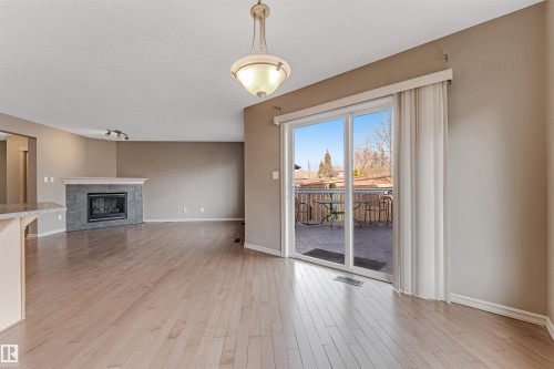 Spacious room with wood-finish flooring, a tile-surround fireplace, and a sliding glass door opening to an outdoor deck - 1431 Hodgson Way, Edmonton, AB - Indoor With Fireplace