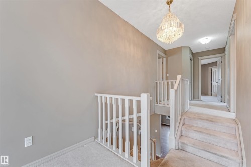 Upper landing featuring a crystal chandelier, carpeted flooring, and white railing - 1431 Hodgson Way, Edmonton, AB - Indoor Photo Showing Other Room