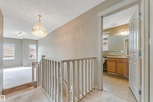 Upper-level landing featuring a decorative chandelier, carpeted flooring, and white painted railings - 1431 Hodgson Way, Edmonton, AB - Indoor Photo Showing Other Room