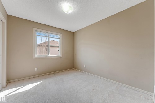 Carpeted interior room with neutral-toned walls, a single window, and a ceiling-mounted light fixture - 1431 Hodgson Way, Edmonton, AB - Indoor Photo Showing Other Room