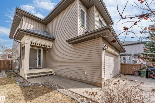 Two-story residence featuring light brown horizontal siding, a covered front porch with lattice detailing, and an attached single-car garage with a panel door - 1431 Hodgson Way, Edmonton, AB - Outdoor With Deck Patio Veranda
