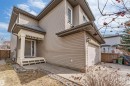 Two-story residence featuring light brown horizontal siding, a covered front porch with lattice detailing, and an attached single-car garage with a panel door - 1431 Hodgson Way, Edmonton, AB  - Outdoor With Deck Patio Veranda 