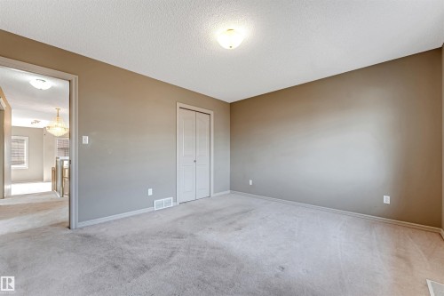 Carpeted room featuring neutral-toned walls, white trim, and a bi-fold door closet - 1431 Hodgson Way, Edmonton, AB - Indoor Photo Showing Other Room