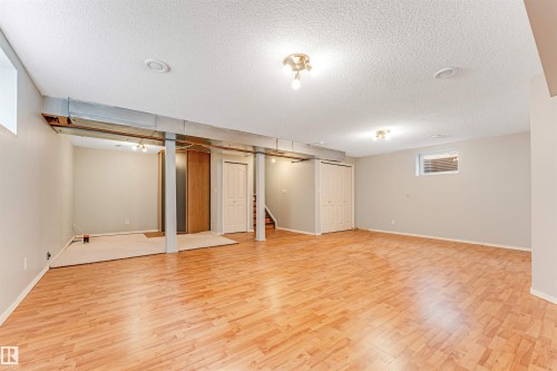 Spacious lower level featuring wood-finish flooring, light neutral walls, recessed lighting, and a window with horizontal blinds - 1431 Hodgson Way, Edmonton, AB - Indoor