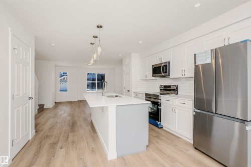 Open-concept kitchen with a central island featuring a stainless steel sink and pendant lighting - 9552 Carson Bend Bend, Edmonton, AB - Indoor Photo Showing Kitchen With Upgraded Kitchen