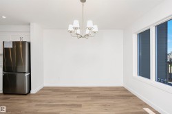 Spacious room featuring wood-finish flooring, white walls, and a multi-light chandelier - 