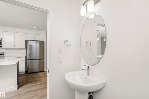 Pedestal sink with chrome faucet and oval mirror, complemented by an overhead two-light fixture - 9552 Carson Bend Bend, Edmonton, AB - Indoor Photo Showing Other Room
