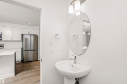 Pedestal sink with chrome faucet and oval mirror, complemented by an overhead two-light fixture - 