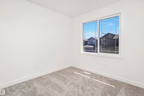 Room featuring a large window with white framing, light-toned walls, and grey carpet flooring - 9552 Carson Bend Bend, Edmonton, AB - Indoor Photo Showing Other Room