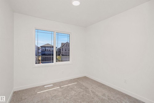 Bright interior space featuring a double window with grid patterns, recessed ceiling lighting, light gray carpet, and white baseboards - 9552 Carson Bend Bend, Edmonton, AB - Indoor Photo Showing Other Room
