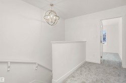 Bright landing area featuring a contemporary spherical chandelier and light grey carpeting - 