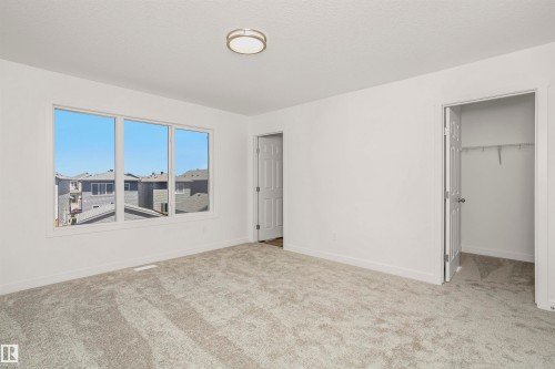 Bright interior room featuring a triple window, neutral carpet, and a flush-mount ceiling light - 9552 Carson Bend Bend, Edmonton, AB - Indoor Photo Showing Other Room