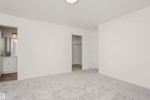 Plush grey carpeting and a neutral color palette define this room, featuring a built-in closet with shelving and a contemporary ceiling fixture - 9552 Carson Bend Bend, Edmonton, AB - Indoor Photo Showing Other Room