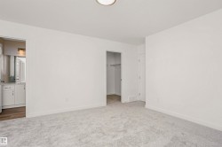 Plush grey carpeting and a neutral color palette define this room, featuring a built-in closet with shelving and a contemporary ceiling fixture - 