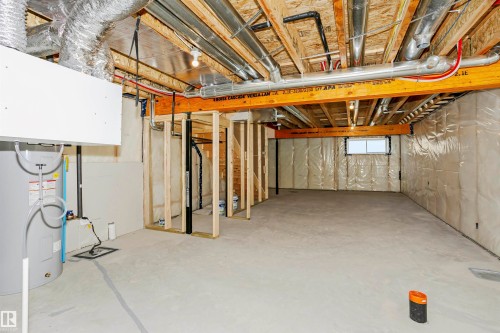 Unfinished lower level featuring exposed ceiling joists, concrete flooring, and a water heater - 9552 Carson Bend Bend, Edmonton, AB - Indoor Photo Showing Basement
