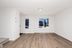 Open concept living area featuring contemporary wood-finish flooring, white walls, and a recessed ceiling light fixture - 