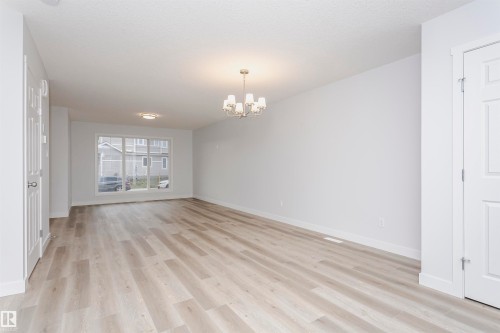 Spacious interior room featuring light wood-finish flooring, white walls, and a large multi-pane window - 9564 Carson Bend Bend, Edmonton, AB - Indoor