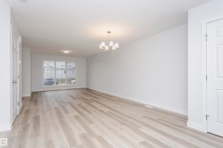 Spacious interior room featuring light wood-finish flooring, white walls, and a large multi-pane window - 