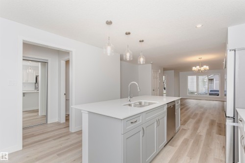 Spacious kitchen island featuring a double-basin stainless steel sink, contemporary faucet, and light gray cabinetry - 9564 Carson Bend Bend, Edmonton, AB - Indoor Photo Showing Kitchen With Double Sink