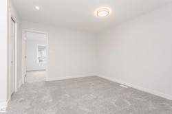 Spacious room featuring light gray carpeting, white painted walls, white trim, a flush mount ceiling light, and a recessed ceiling light - 