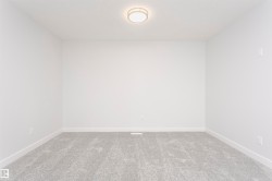 Neutral white walls featuring a contemporary flush-mount ceiling light, light gray carpeting, and white baseboards - 