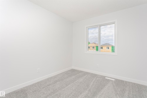 Bright room featuring a large window, plush gray carpet, and crisp white walls and trim - 9564 Carson Bend Bend, Edmonton, AB - Indoor Photo Showing Other Room