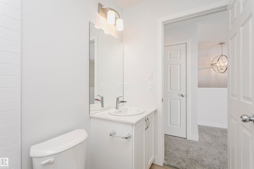 Bathroom featuring a white vanity with a single basin sink, wall-mounted mirror, and brushed nickel hardware - 9564 Carson Bend Bend, Edmonton, AB - Indoor Photo Showing Bathroom